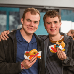 two young men holding donuts